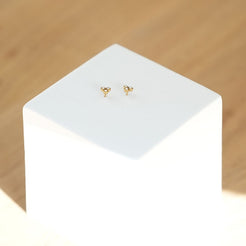 Gold earrings on a white stand with a wooden background