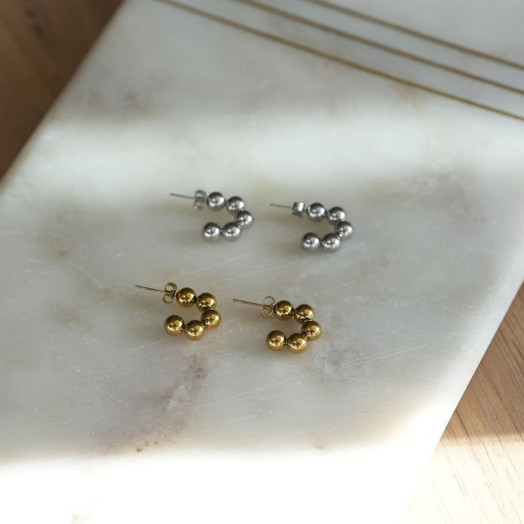 Gold and silver beaded earrings on a marble surface