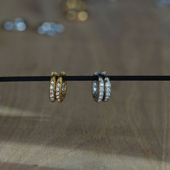 Gold and silver stainless steel pavé huggie hoop earrings displayed side by side