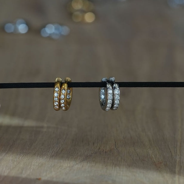 Gold and silver stainless steel pavé huggie hoop earrings displayed side by side