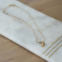 Gold necklace with a moon pendant on a marble surface