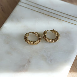 Gold hoop earrings on a marble surface