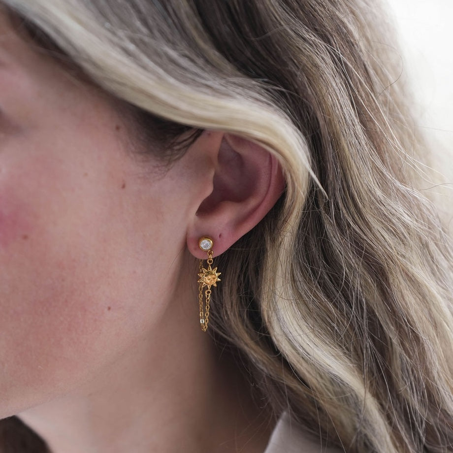 Close-up of a person wearing a gold earring with a star design.