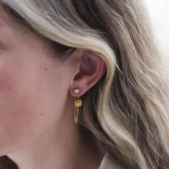 Close-up of a person wearing a gold earring with a star design.