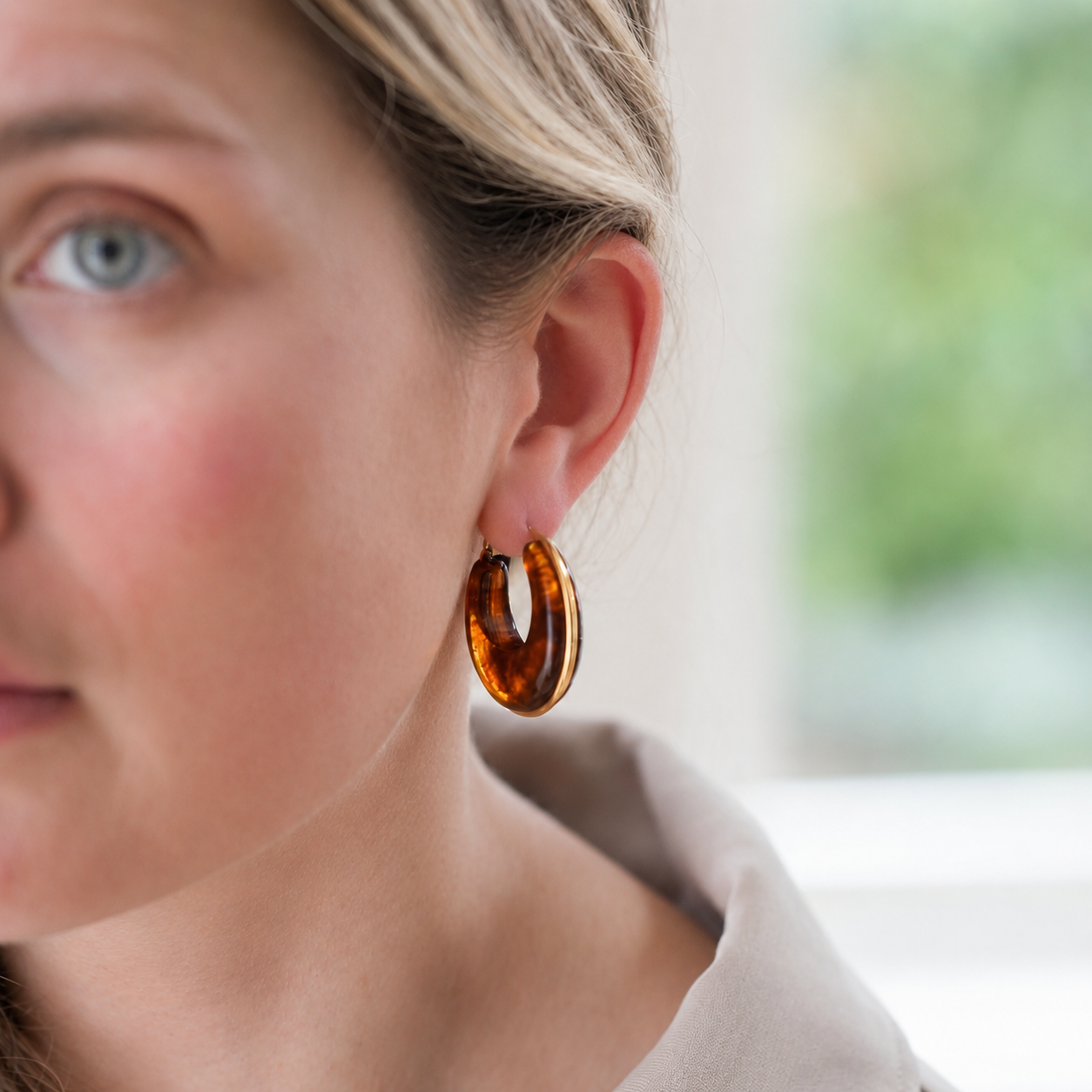 Close-up of a person wearing a tortoiseshell hoop earring with a blurred background